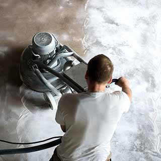 A heavy industrial grinder is used to prepare a concrete floor for epoxy coating