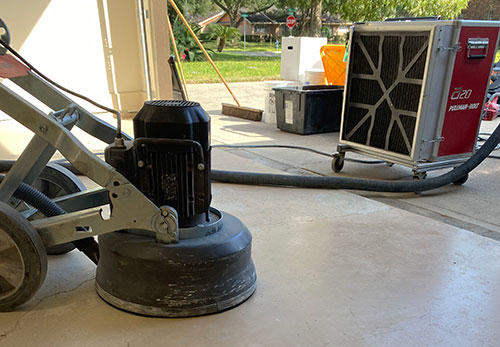 Heavy duty floor grinding equipment connects to a large HEPA filtered air scrubber to mitigate dust during an epoxy floor coating project